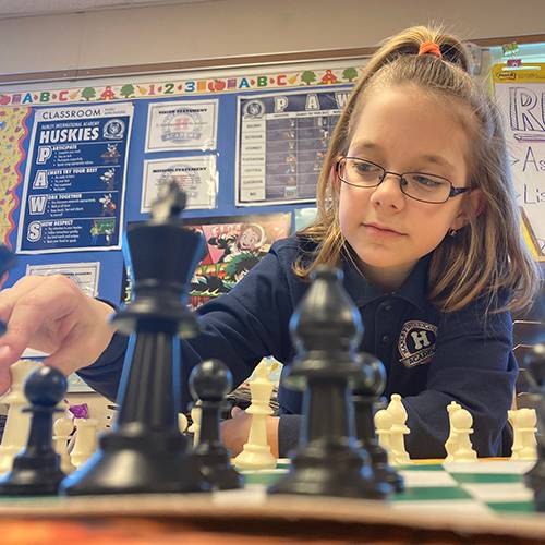 Middle school girl looking over a chessboard as she determines her next move.